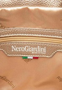 Guldstruktureret stofinteriør med en lynlås lomme. Logoet "NeroGiardini MADE IN ITALY" trykt over et lille italiensk flagdetalje.