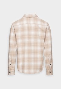 Beżowa i biała koszula w kratę z długim rękawem i zapinanymi na guziki mankietami, pokazana z tyłu na jednolitym jasnym tle.