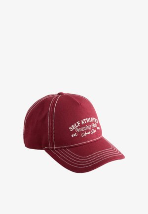 Punane puuvillane pesapalli nokamüts valgete õmblustega, mille ees on tikitud tekst "SELF ATHLETICS Country Club". Kaardus visori disain.
