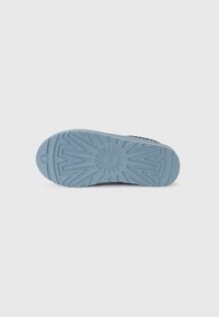 Semelle de chaussure en caoutchouc bleu avec motif de bande de roulement en zigzag et motif en forme de rayons de soleil sur fond blanc.
