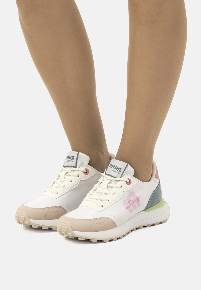 Zapatillas deportivas blancas con acentos en tonos pastel, que cuentan con una puntera texturizada, parte delantera con cordones y detalle de logo en el lateral. Suela de goma para mayor tracción.