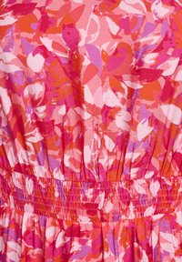 Ryški rožinis, raudonas ir purpurinis gėlėmis raštuotas audinys su susiraukšlėta elastine juosta, kuriančia tekstūrinius raukšles.