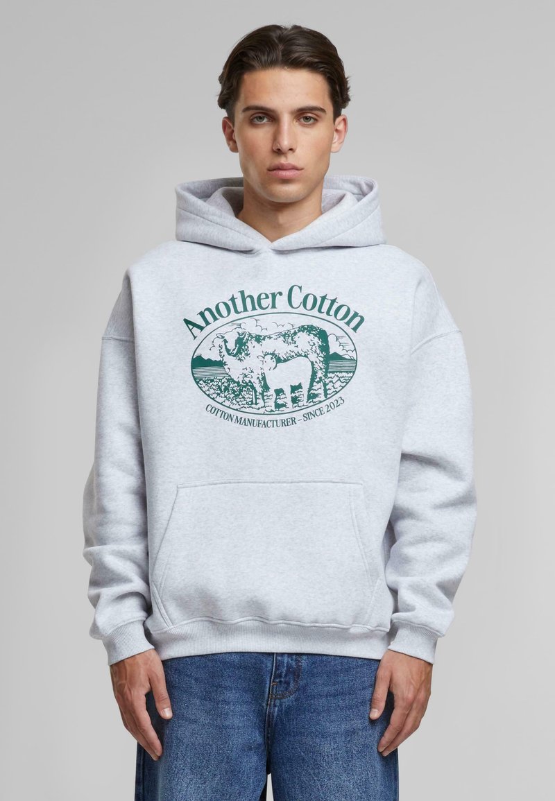 Gray cotton hoodie featuring a front pocket and a green printed logo of a cow with the text “Another Cotton” and “COTTON MANUFACTURER - SINCE 2023.”