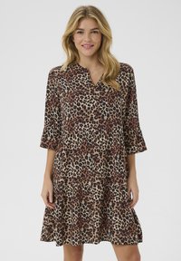 Luipaardprint jurk met een V-hals, driekwart mouwen en een gelaagde rok; de stof heeft een gladde textuur in bruin en beige tinten.