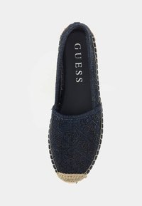 Blue denim espadrille with a textured upper, beige jute trim at toe, and black inner lining featuring the brand name "GUESS."