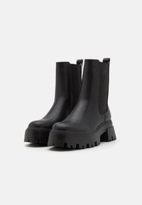 Black leather ankle boots with a chunky platform sole, elastic side panels, and pull tabs, featuring a smooth texture and rounded toe.