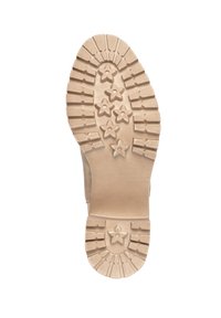 Suola in gomma di colore beige chiaro, caratterizzata da un motivo a stella e linee in rilievo per migliorare la trazione, con tacco arrotondato e superficie testurizzata.