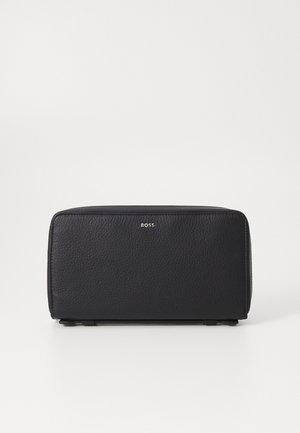 Svart skinn kosmetikkveske med en teksturert overflate, rektangulær form, glidelås lukking og en liten sølvlogo på forsiden.