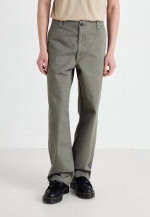 Green cotton pants with a straight leg design, featuring a button closure and front pockets. Worn with black shoes.