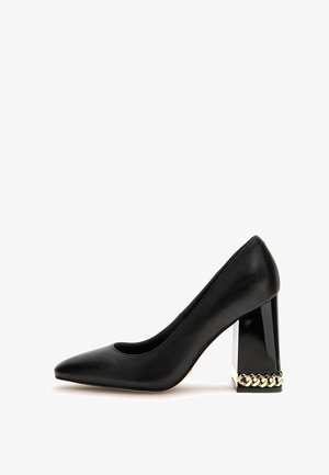 Pompe en cuir noir avec un bout pointu et un talon épais transparent. Talon accentué par un détail en chaîne dorée autour de la base.