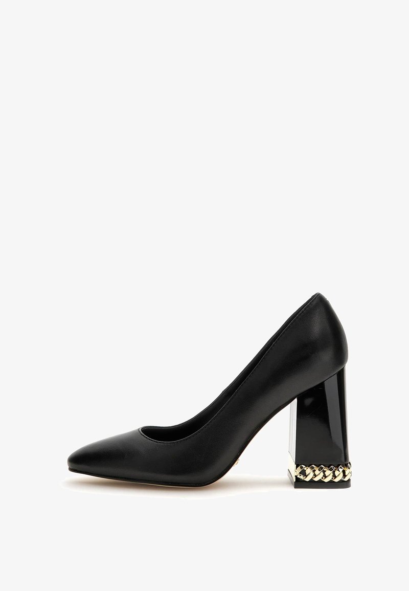 Pompe en cuir noir avec un bout pointu et un talon épais transparent. Talon accentué par un détail en chaîne dorée autour de la base.