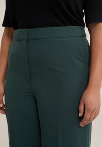 Zelené sk tailored kalhoty s hladkou texturou, vysokým pasem, předním skladem a skrytým zipem na boku.