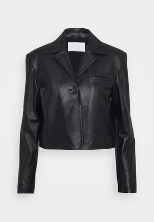 Blazer en cuir noir court avec manches longues, col cranté, fermeture par un bouton unique et une petite poche poitrine sur fond uni.