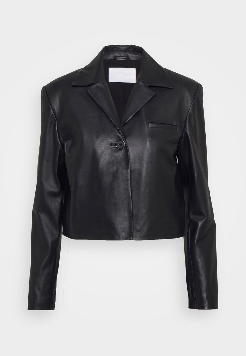 Blazer en cuir noir court avec manches longues, col cranté, fermeture par un bouton unique et une petite poche poitrine sur fond uni.