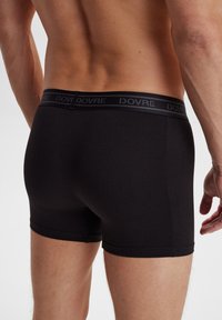 Sorte bomuldsboksershorts har en glat tekstur, længde til midt på låret og et mørkt elastisk taljebånd med "DOVRE" branding.