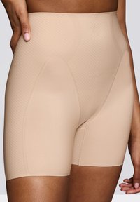 Shorts modellanti a vita alta beige, caratterizzati da un motivo a spina di pesce testurizzato, tessuto liscio e design aderente per supporto e comfort.
