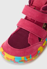 Rosa Wildleder- und Mesh-Sneaker mit zwei verstellbaren Klettverschlüssen. Die mehrfarbige Gummisohle hat ein lebendiges Muster mit blauen, gelben und roten Akzenten.