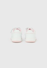 Baskets pour enfants blanches et roses avec des bandes Velcro, vues de dos sur un fond blanc uni.