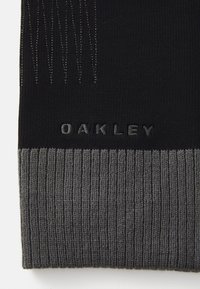 Black knit beanie with a ribbed gray cuff. Features subtle textured patterns and "OAKLEY" embossed in gray on the side.