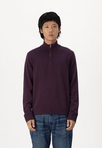 Maglione con collo zip viola realizzato in tessuto a maglia, con polsini e orlo a coste, abbinato a jeans in denim blu. Design semplice e moderno.