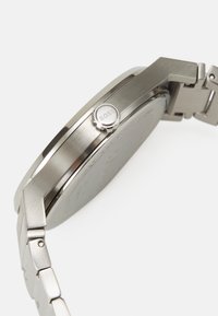 Stainless steel wristwatch with a rounded case, featuring a silver crown marked "BOSS," and a brushed metal bracelet with smooth links.