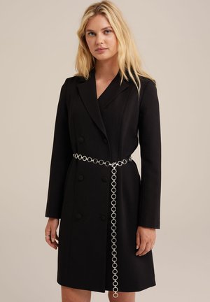 Musta kaksirivinen takki pitkillä hihoilla, jossa on hopeinen pyöreä ketjuhihna ja tyylikäs, muotoiltu design. Pehmeä, teksturoitu kangas.