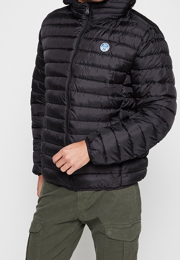 Sort pufferjakke med horisontalt quiltet mønster, fuld lynlås og fastgjort hætte. Har et rundt blåt logo på brystet.