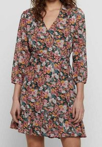 Blumenkleid mit rosa, gelben und grünen Blumen auf einem hellen Hintergrund. Lange Ärmel, taillierter Schnitt und rüschierter Saum.