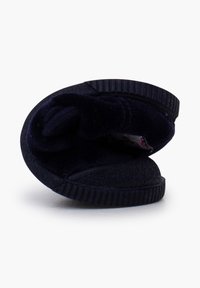Zapatilla de color azul marino oscuro con parte superior de tela suave, diseño enrollado, suela texturizada y un borde flexible para facilitar el uso.