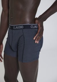 Bokserki w ciemnym granacie z okrągłym wzorem. Wykonane z elastycznego materiału, z solidnym elastycznym pasem z logo "CLAUDIO".