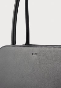 Γκρι δερμάτινη τσάντα χειρός με ομαλή υφή, που διαθέτει δύο μαύρες λαβές και ένα μικρό ανάγλυφο λογότυπο "BOSS" στο μπροστινό μέρος.