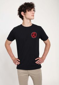 Czarny t-shirt wykonany z materiału bawełnianego z czerwonym logiem Avengers na lewej stronie klatki piersiowej. Krótkie rękawy i klasyczny dekolt typu crew neck.