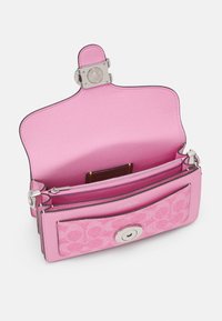 Portefeuille rose en cuir et tissu avec rabat ouvert, montrant un compartiment zippé et une poche avant avec fermoir à tour argenté.