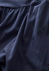 Marinblått bomullstyg med en mjuk textur, med en samlad design upptill och flödande draperingar nedtill.