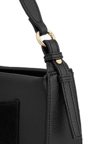 Borsa a mano in pelle nera con finitura testurizzata, dotata di hardware circolare in tonalità oro e tracolla regolabile fissata con dettagli in pelle cuciti.