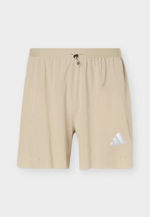 Beige athletic shorts with elastic waistband and drawstring, featuring a small white Adidas logo on the lower right leg.