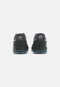 Zapatillas Nike Air negras con una parte superior de cuero suave, cuello acolchado y suela de goma con una suela transparente y acentos plateados.