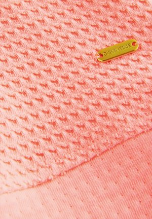 Texturirana koralna tkanina z diamantnim vzorcem, z gladkim robom in zlato etiketo z napisom "DOWNTIME."