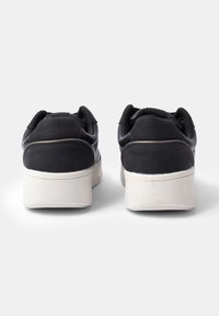 Black sneakers with a smooth leather upper, cushioned collar, and white rubber sole. The design features a low profile and minimal detailing.