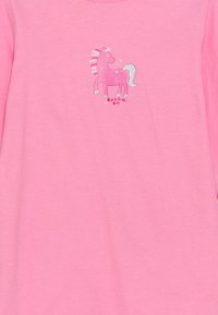 Pink long-sleeve shirt with a unicorn graphic in pink and silver glitter. Text below reads “dream on.” Soft, cotton material.