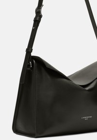 Czarna skórzana torba na ramię o trójkątnym kształcie, gładkiej fakturze i regulowanym pasku, z metalowymi detalami w kolorze srebrnym oraz wytłoczonym logo.