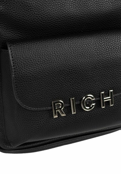 Bolso de cuero negro con una superficie texturizada, tapa frontal y letras en tono dorado que dicen "RICH" como detalle notable. Forma rectangular.