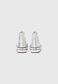 Sneakers high-top in pelle patent argento con suole in gomma nere e bianche, caratterizzati da un logo applicato sul lato esterno.