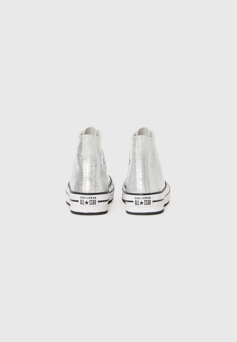 Zapatillas altas de charol plateado con suelas de goma negras y blancas, que presentan un parche con el logo en el lado exterior.