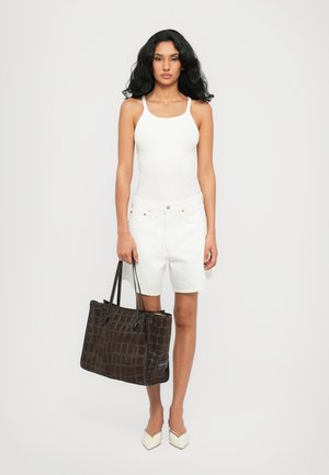 Witte tanktop, witte denim shorts en puntige beige schoenen. Donkerbruine totebag met krokodillenstructuur en zwarte handvaten.