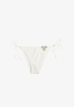 Weiße Bikinihöschen mit seitlichen Bindebändern und einem kleinen Cluster aus silbernen, blumenförmigen Verzierungen auf der vorderen rechten Seite.