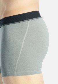 Harmaat boxerit mustalla ribbausvyöllä. Ominaisuuksiin kuuluu sileä pinta ja lisäksi kontrastivärinen ommel saumoissa.