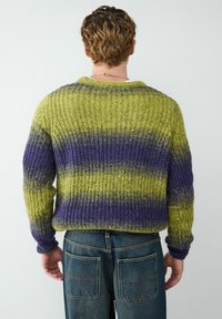 Gebreide trui met groene, gele en paarse horizontale strepen, iets relaxte pasvorm, geribbelde boorden en een ronde halslijn.