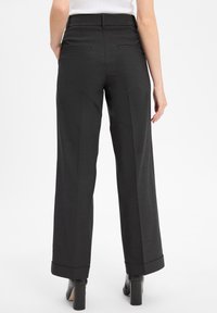 Zwarte, wijde broek met een gestructureerde stof, hoge tailleband en twee achterzakken. Opgerolde mouwen en een getailleerde pasvorm verbeteren het ontwerp.