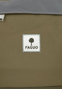Borsa in tela di colore verde oliva, con un ribattino grigio, caratterizzata da una toppa bianca cucita con un logo ad albero e il testo "FAGUO" sotto il logo.
